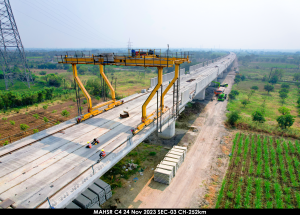 A gantry crane positions large concrete segments to construct a noise barrier